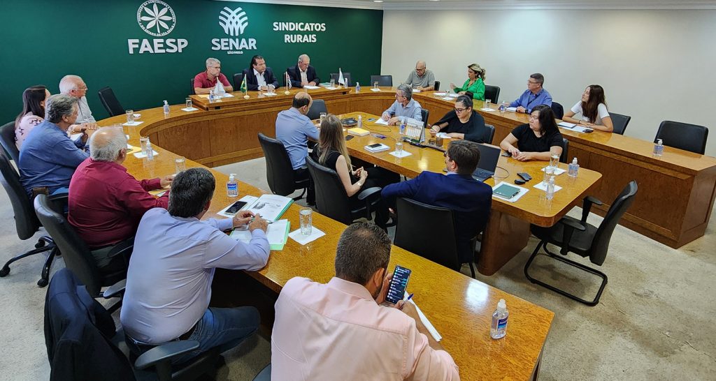 Presidência, diretores e membros da comissão de grãos em mesa em sala de reunião, na FAESP.  